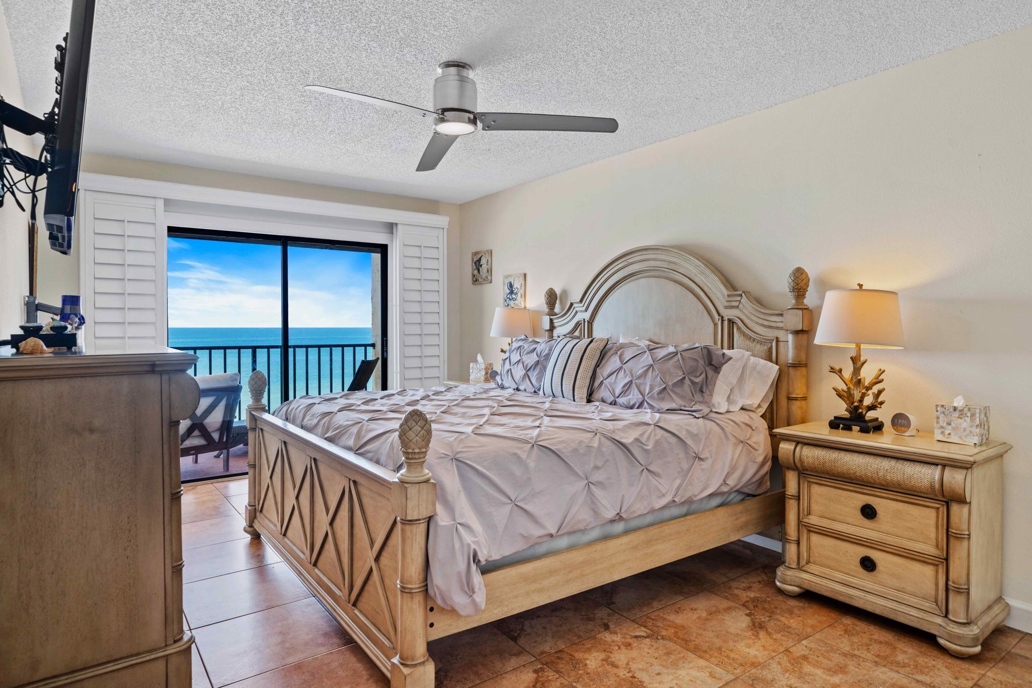 Ein Schlafzimmer mit Bett, Nachttischen, Deckenventilator und Meerblick.