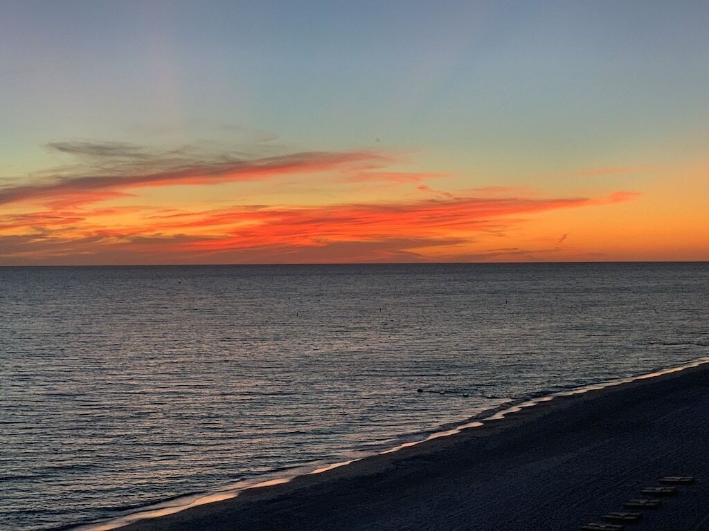 A beach with a sunset over the ocean.