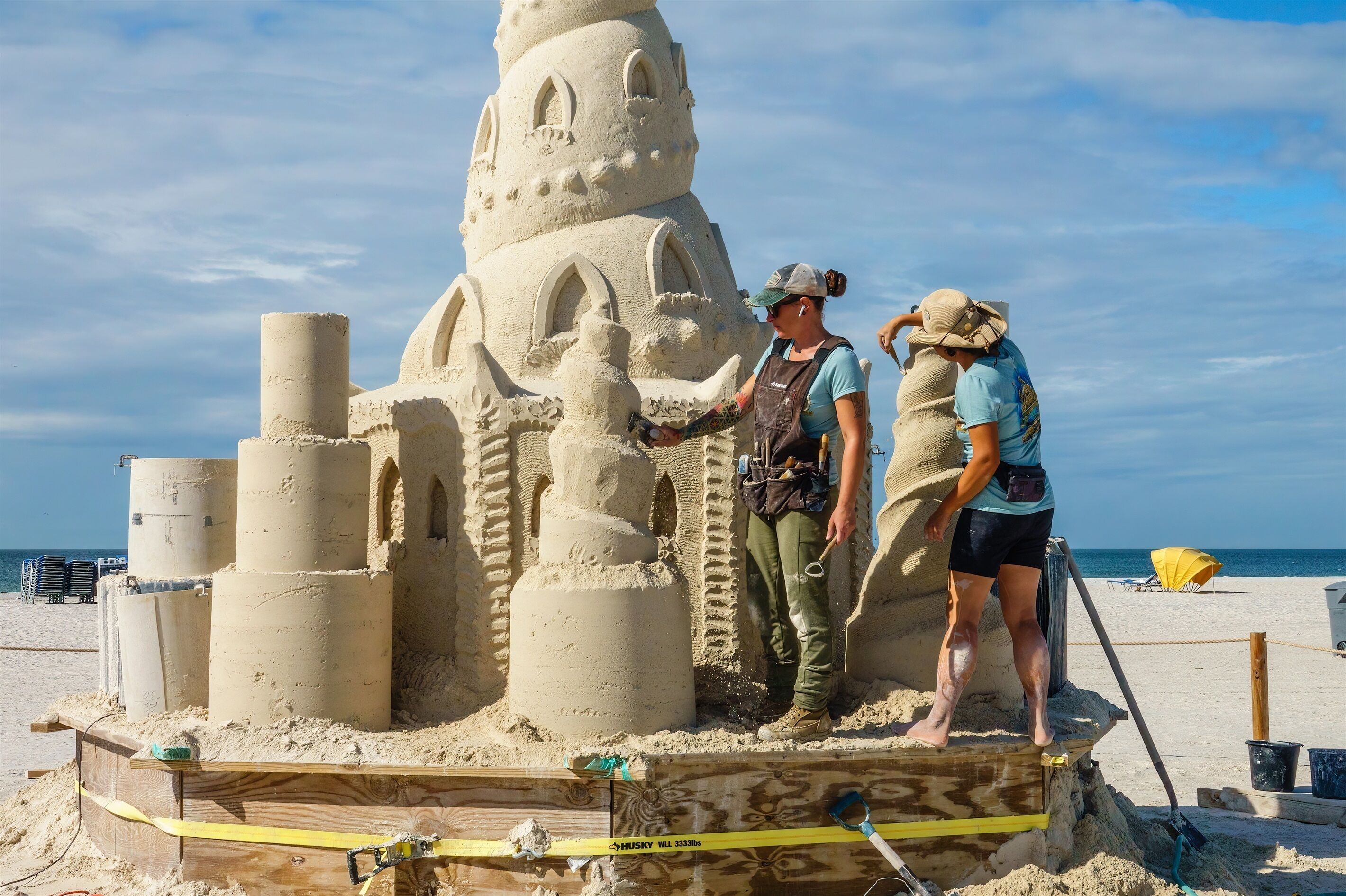 Ein großes Sandschloss am sandigen Strand unter blauem Himmel.
