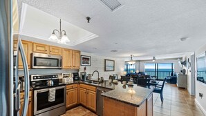 Una cocina moderna con electrodomésticos de acero inoxidable, armarios de madera, una isla grande y vistas al exterior.
