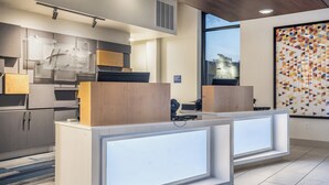A modern reception desk with a wooden accent, a large window with a view, and a geometric patterned wall. - Holiday Inn Express & Suites Platteville (Platteville)