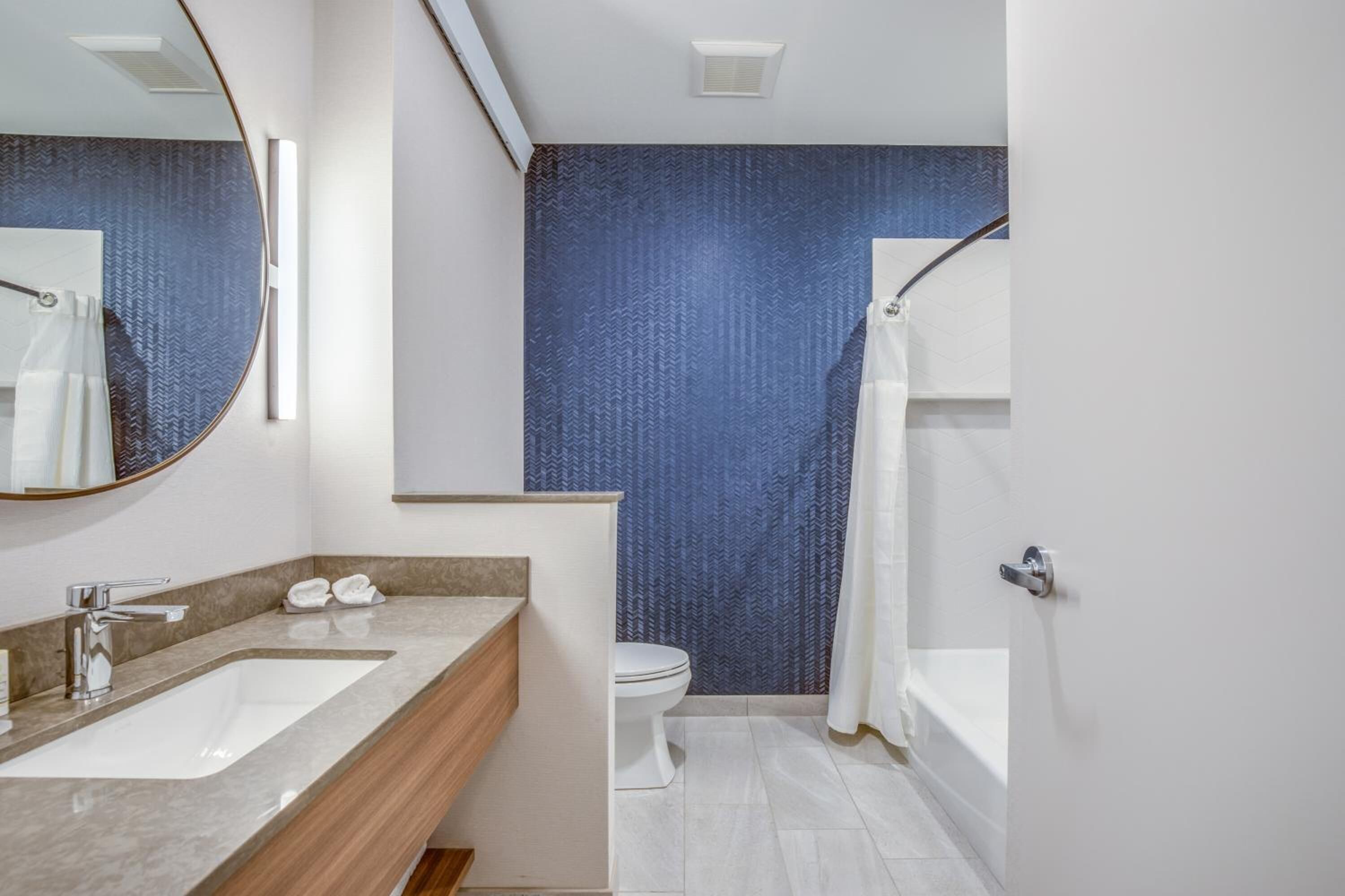 Un baño moderno con un espejo grande, un lavabo, un inodoro y una bañera.
