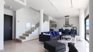 A modern living room with a staircase, a sofa set, and a dining area.