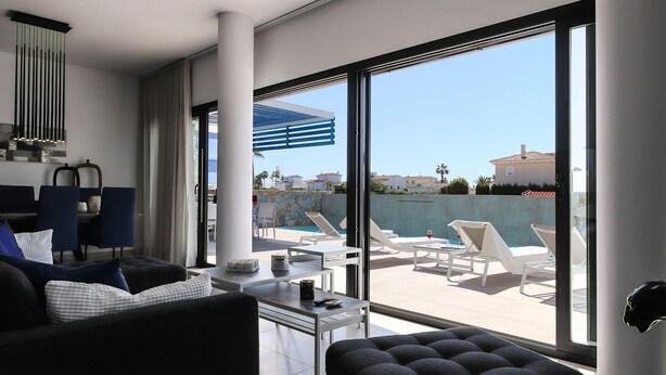 A modern hotel room with a balcony, large windows, and a pool area visible outside.
