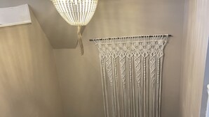 Un escalier avec une rampe blanche, une décoration murale en macramé et un luminaire suspendu.