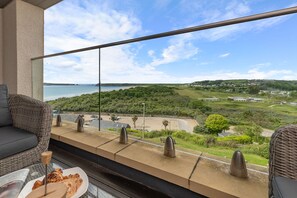 A balcony with a view of a beach and greenery. - Apartment 10 Waterstone House - Sea Views (Tenby)