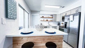 Une cuisine moderne dotée d’un îlot central, d’appareils électroménagers intégrés et d’une grande fenêtre.