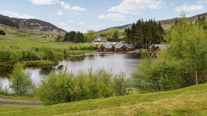 Un entorno junto al lago con cabañas, un pequeño edificio y un sendero que conduce al agua.
