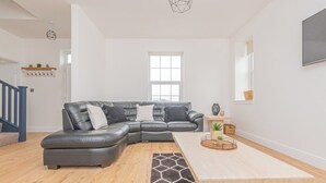 A modern living room with a sectional sofa, a wooden coffee table, and a geometric rug.