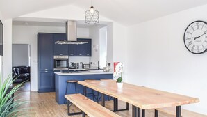 A modern kitchen with a central island, bar stools, and a wooden dining table with benches.