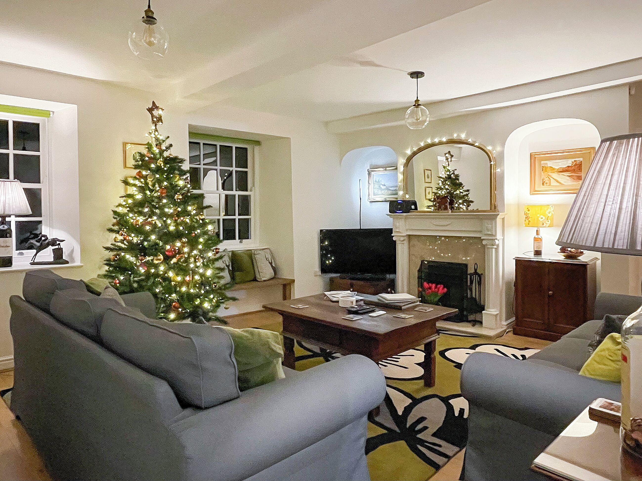 Un salon avec un sapin de Noël, une cheminée et un téléviseur.