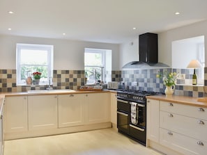 A modern kitchen with a gas stove, oven, and a window with a view.