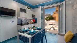 A compact living space with a dining area, kitchenette, and a balcony with a view.
