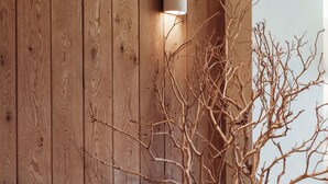 Eine Holzwand mit einer modernen Leuchte, einer Holzskulptur und einem Blumentopf.