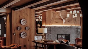 Ein gemütliches, rustikales Interieur mit Holzbalken, einem Kamin und einem Essbereich.