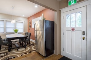 A compact kitchen with a stainless steel refrigerator, a dining table with chairs, and a door with a window and a no-smoking sign. - Walking distance to Niagara Falls (Niagara Falls)
