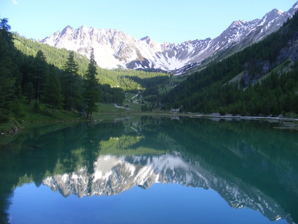 Ein Bergsee mit Spiegelungen von Bäumen und Bergen.