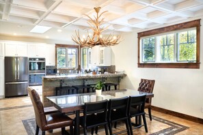 A modern kitchen with a large island, stainless steel appliances, and a unique antler chandelier.