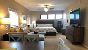 A hotel room with a bed, a desk, a chair, a television, and a ceiling fan.
