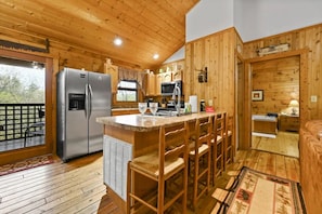 Enjoy cooking in this well-equipped kitchen with a central island, stainless steel appliances, and a wooden bench.