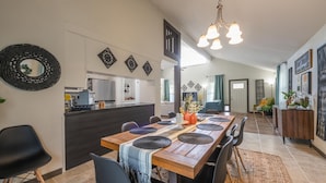Una cucina moderna con mobili scuri, un tavolo da pranzo in legno con sottopiatti neri e un lampadario a sospensione.