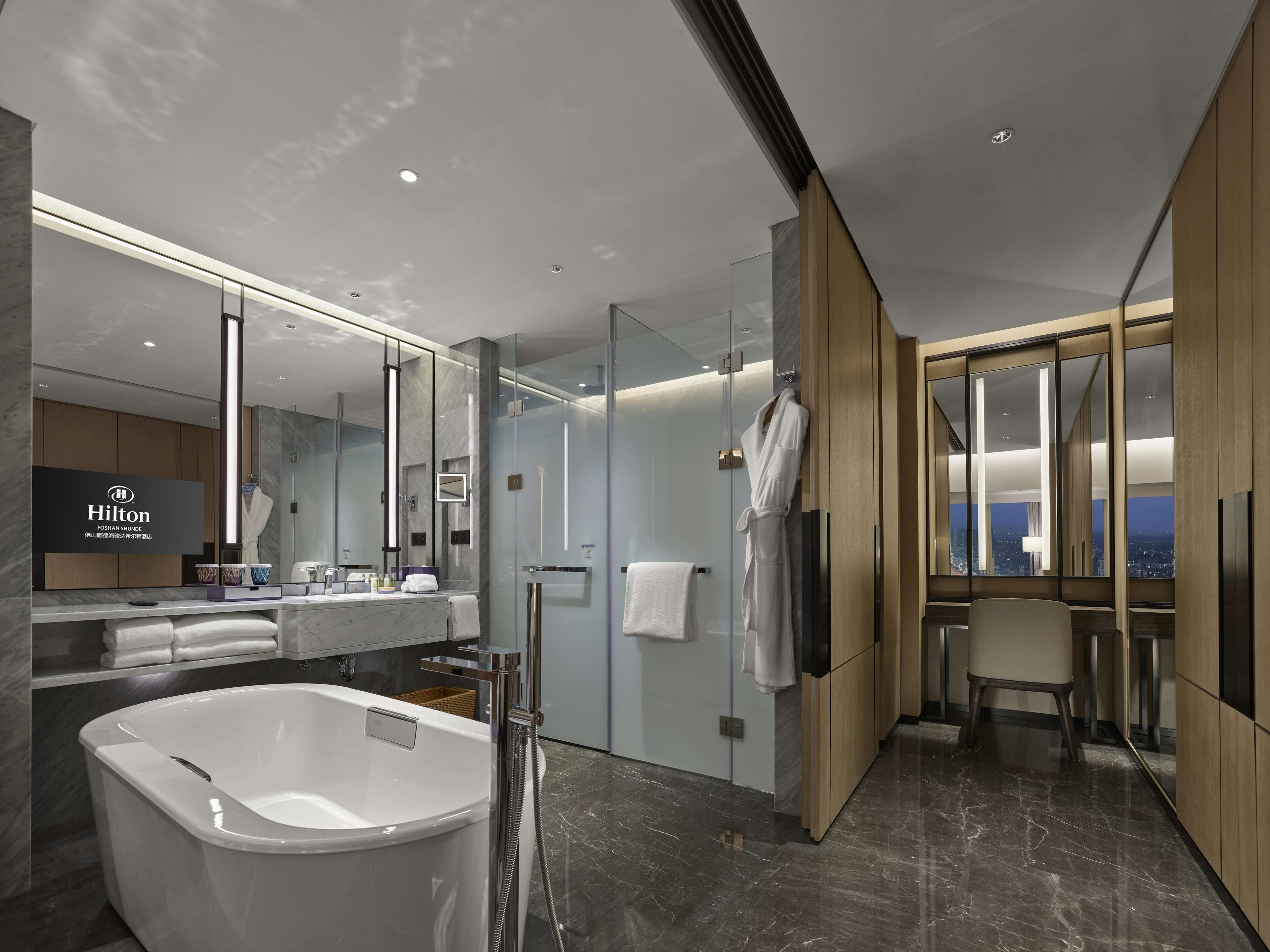 A modern hotel bathroom with a large bathtub, a glass shower enclosure, and a vanity with a mirror.