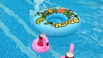 Una piscina con flotadores y latas a la deriva en el agua.