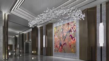 A modern lobby with a large abstract painting, sleek lighting fixtures, and a polished marble floor.
