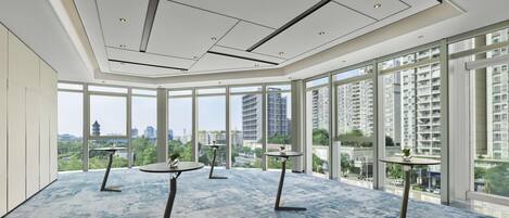 A spacious room with large windows, a modern ceiling design, and a blue carpet.