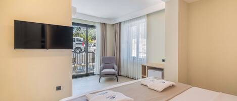 A hotel room with a bed, a TV mounted on the wall, a chair, and a view of the outside through a window.