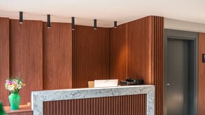 A reception desk with a marble top, wooden paneling, and a green plant. - Seatown Hotel (Kas)