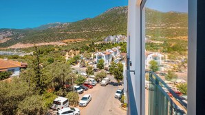 A residential area with a row of white buildings, a parking lot, and a mountainous backdrop. - Seatown Hotel (Kas)