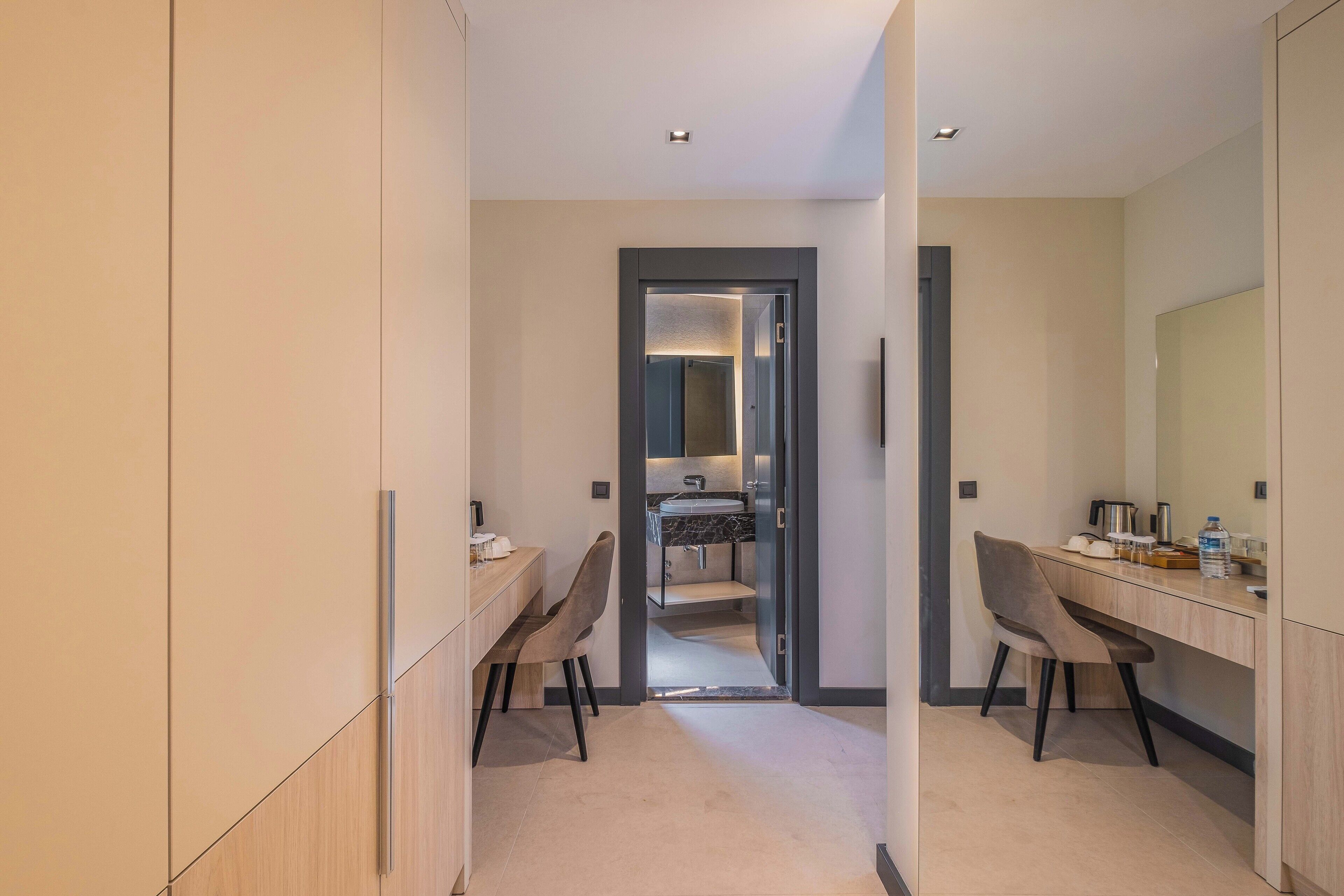 A modern hotel bathroom with a large mirror, two sinks, and a shower area.