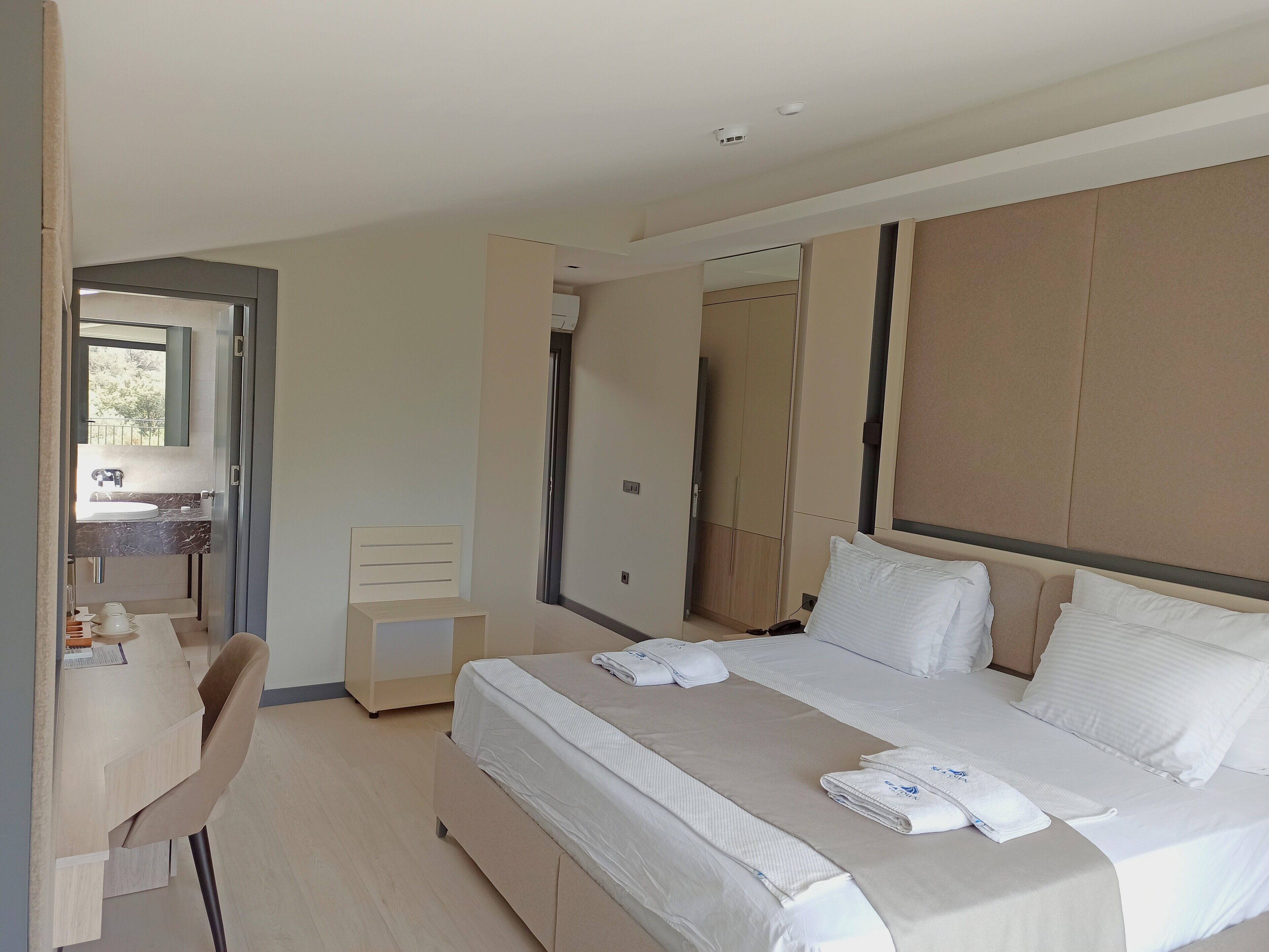 Una habitación de hotel moderna con una cama grande, un escritorio y un baño visible a través de una puerta abierta.