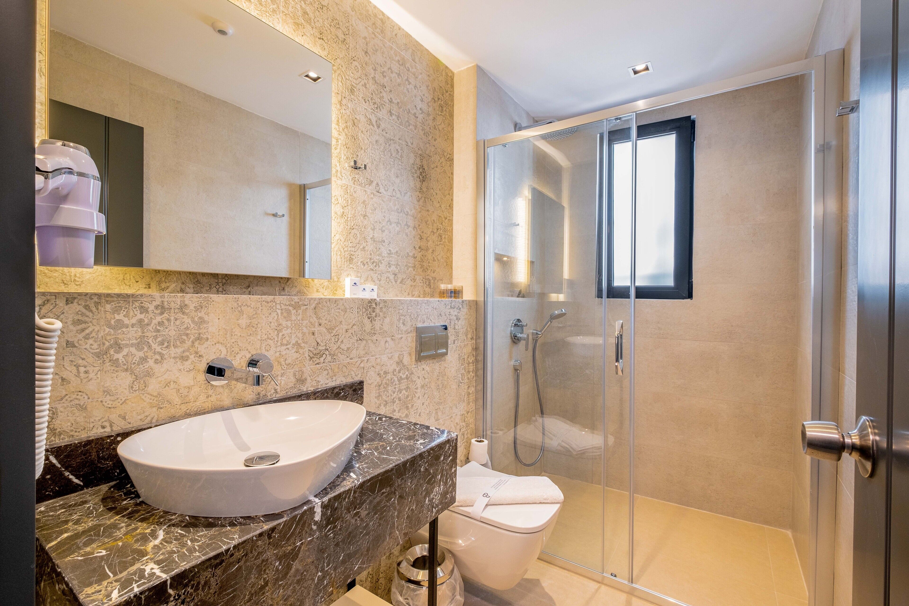 Une salle de bain moderne avec un lavabo en marbre, une douche à parois de verre et des toilettes.