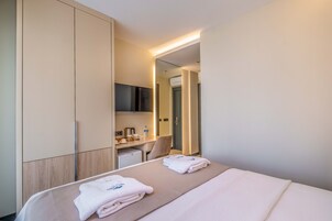 Una habitación de hotel con una cama, un escritorio, una silla y un armario.