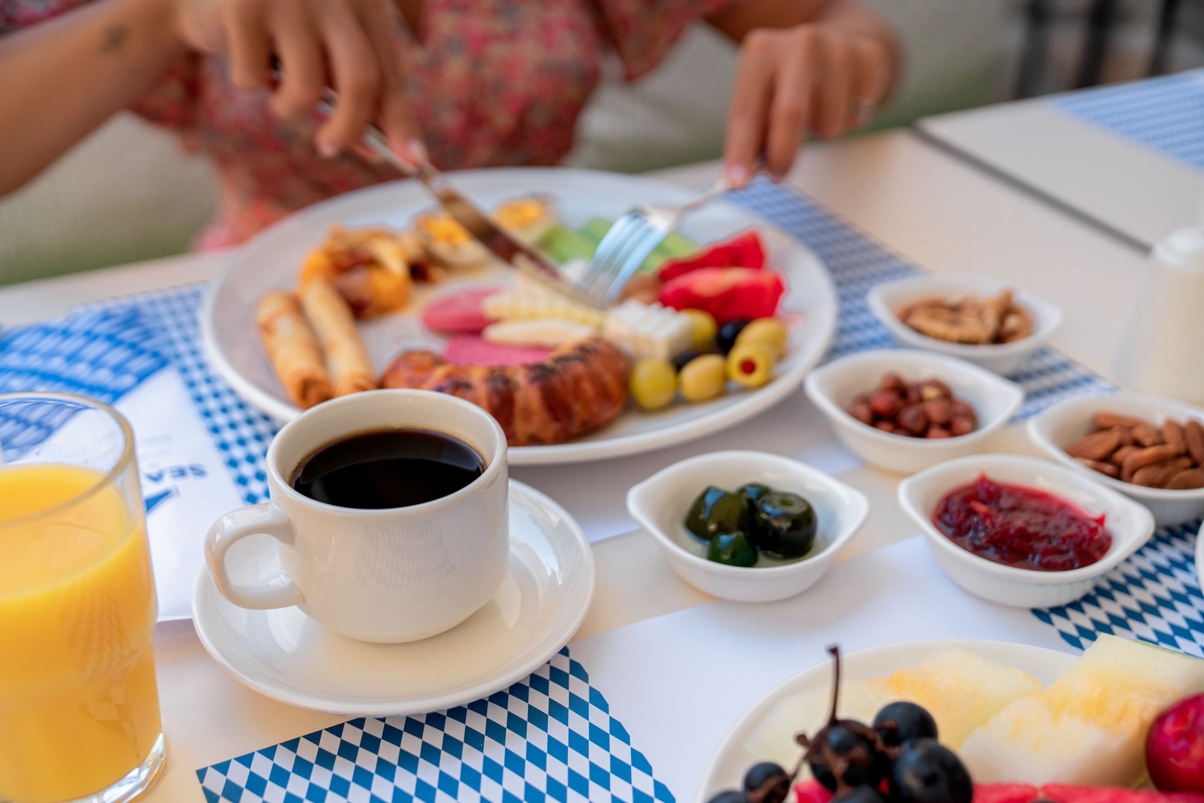En morgenmadsopstilling med en tallerken mad, en kop kaffe og diverse tilbehør.