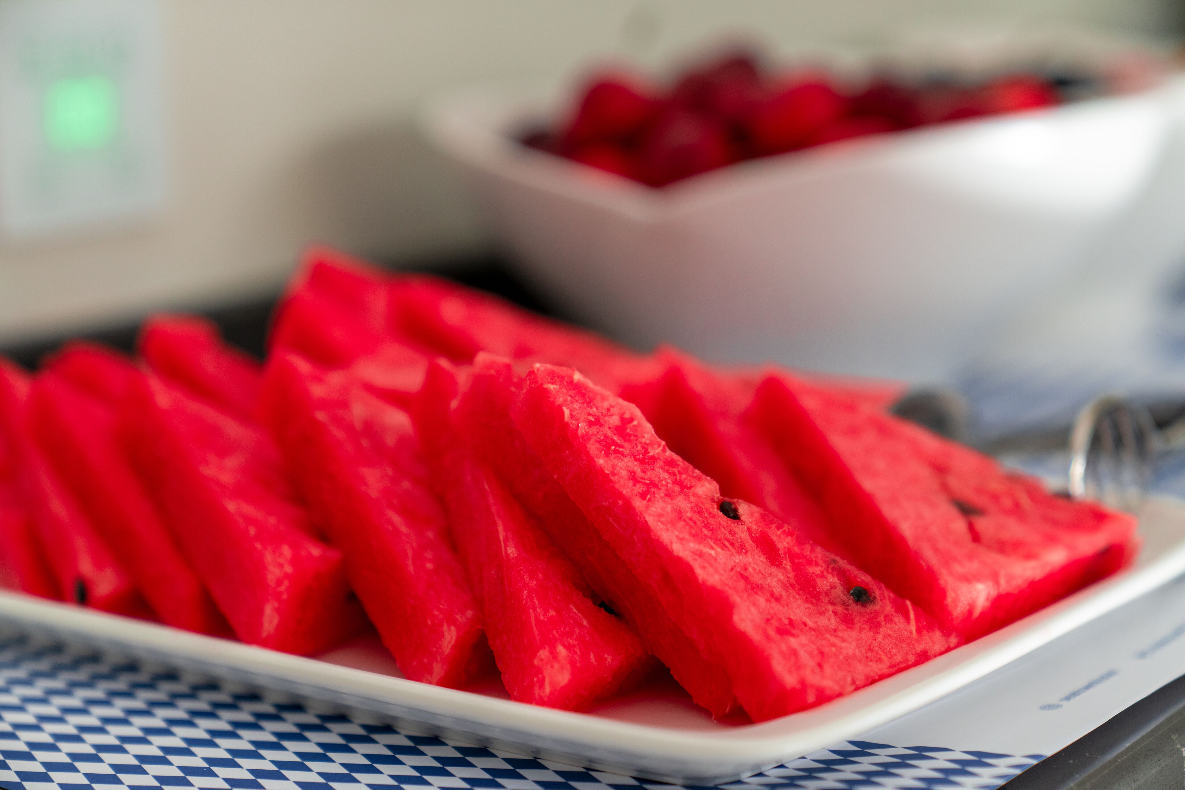 A white plate with watermelon slices on a checkered tablecloth.