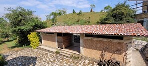 Un pequeño edificio de ladrillo con techo de tejas, un sendero de piedra y un césped verde.