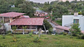 A residential area with houses, some under construction, and a white building with a red roof.
