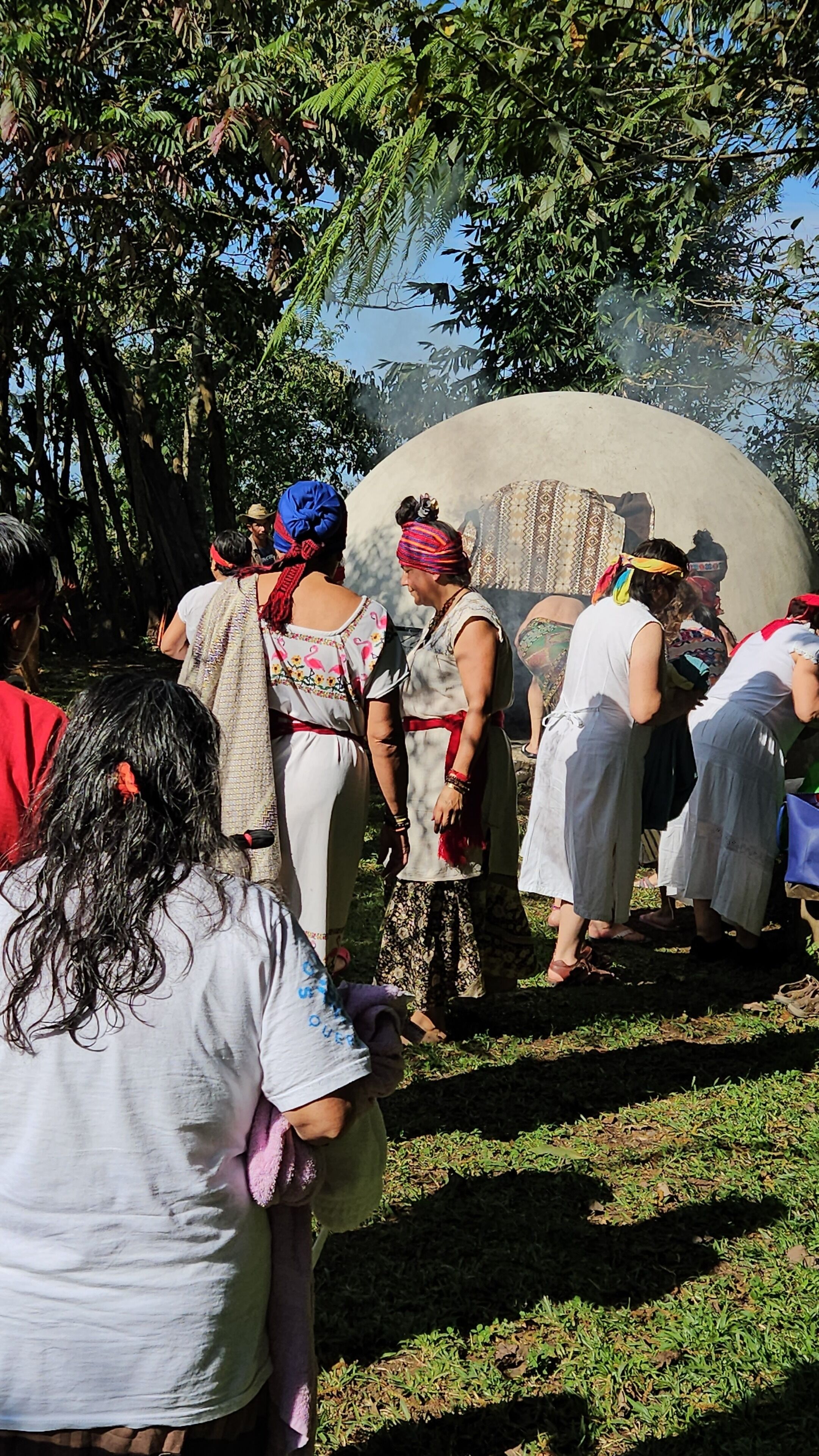 Un grupo de personas reunidas alrededor de una gran estructura circular de concreto en un entorno exterior con árboles al fondo.
