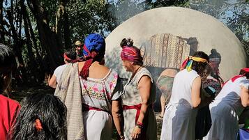 Un grupo de personas reunidas alrededor de una gran estructura circular de concreto en un entorno exterior con árboles al fondo.