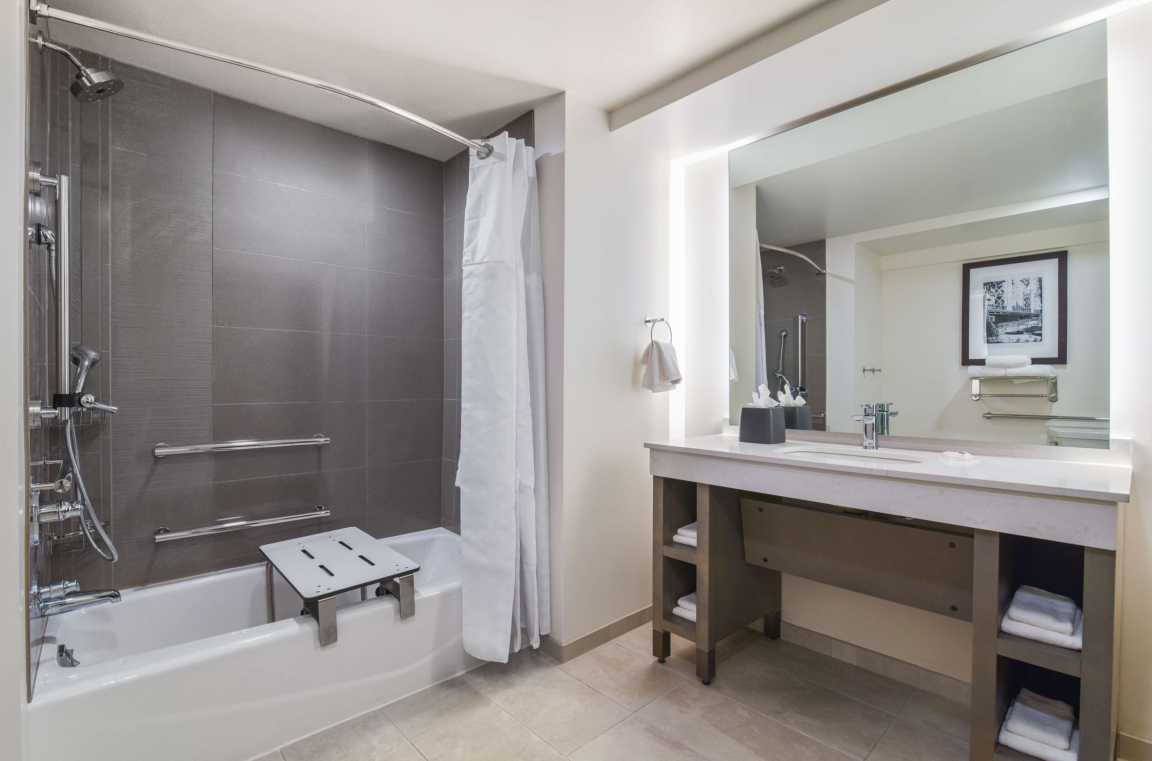 A modern bathroom with a bathtub, shower, and vanity with a large mirror.