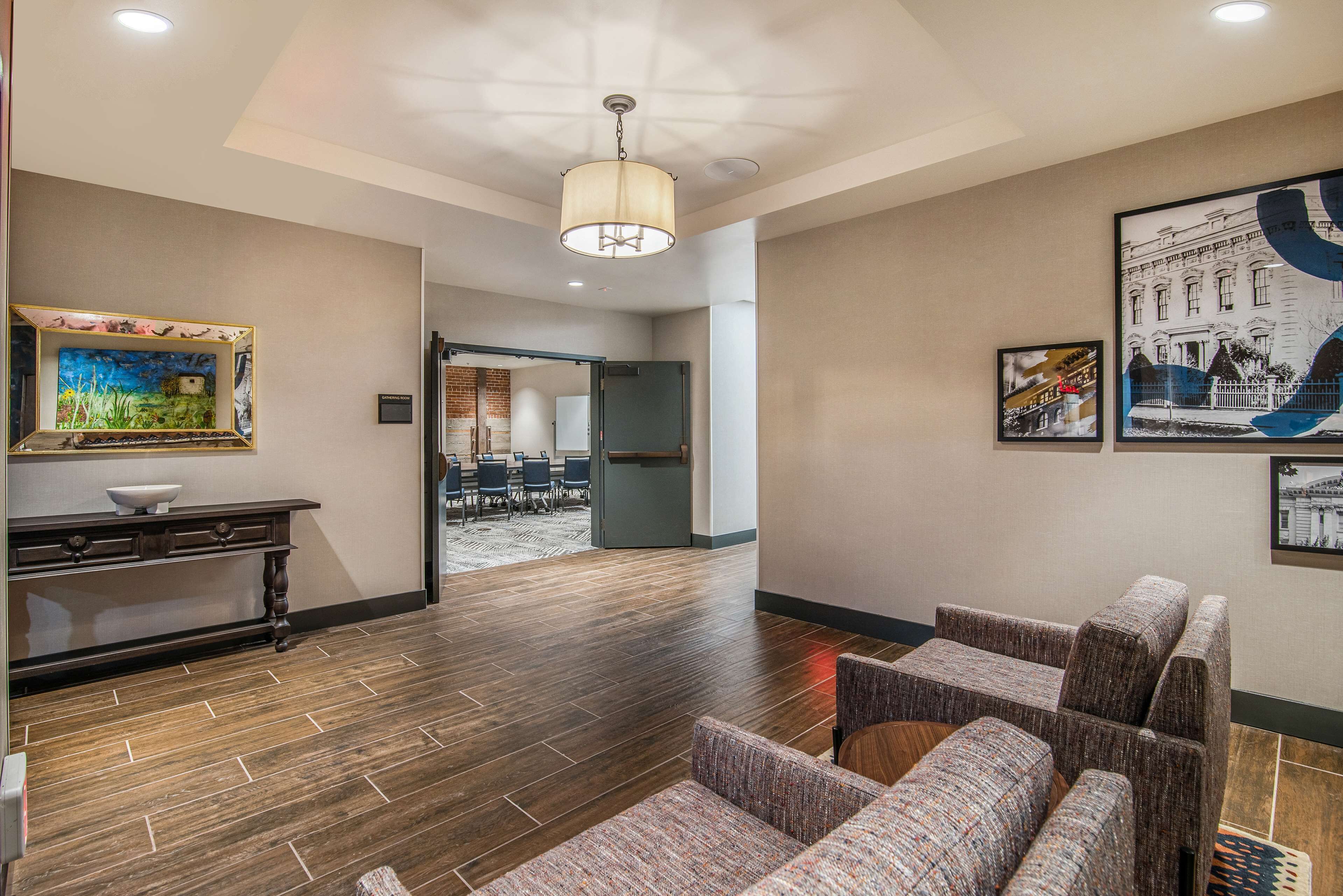 A lobby with a wooden floor, a reception desk, a seating area, and framed artwork on the walls.