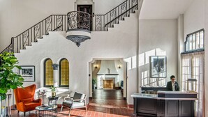 A spacious lobby with a grand staircase, a fireplace, and a reception desk.