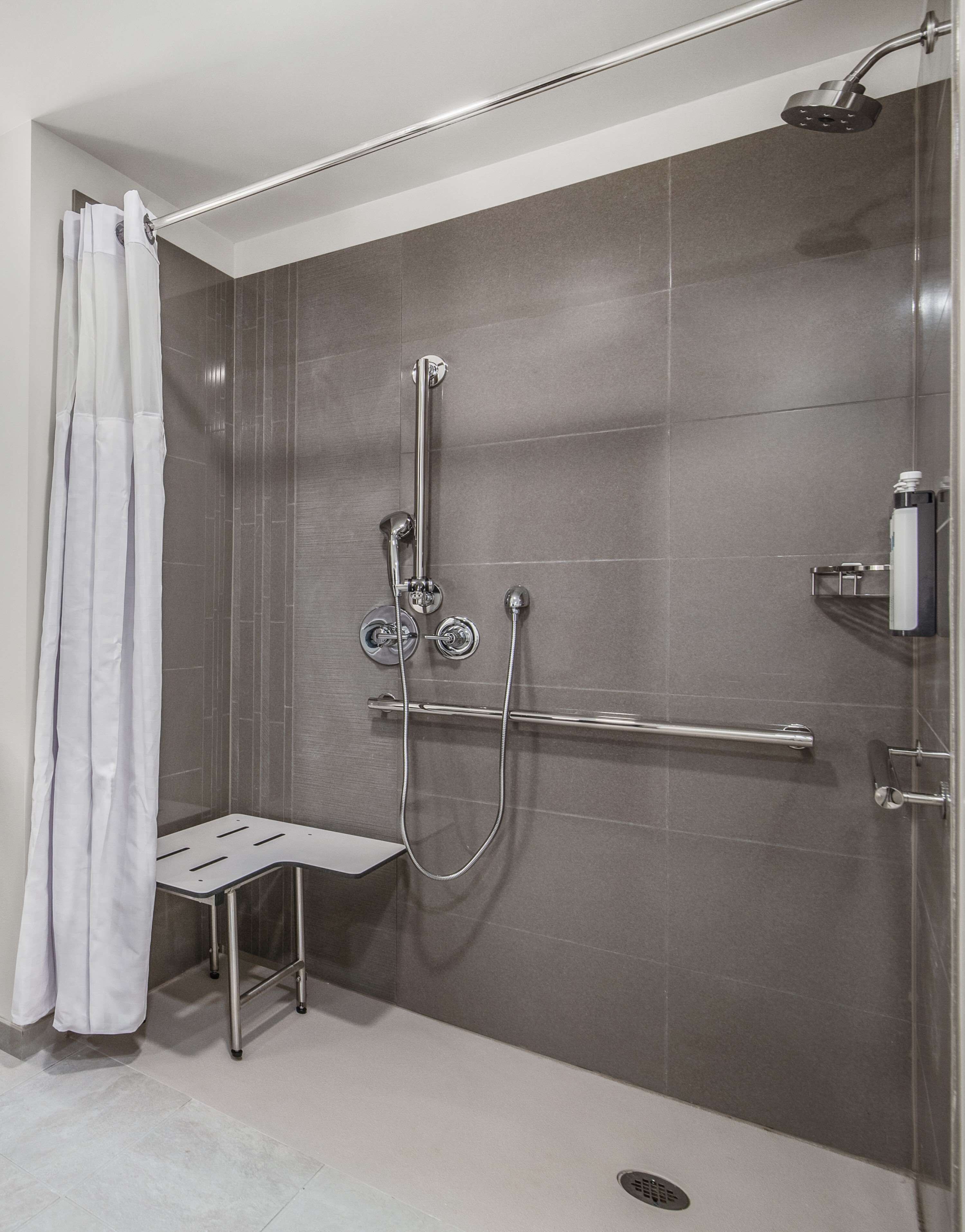 A modern shower area with a handheld showerhead, a fixed showerhead, and a handheld showerhead with a flexible hose.