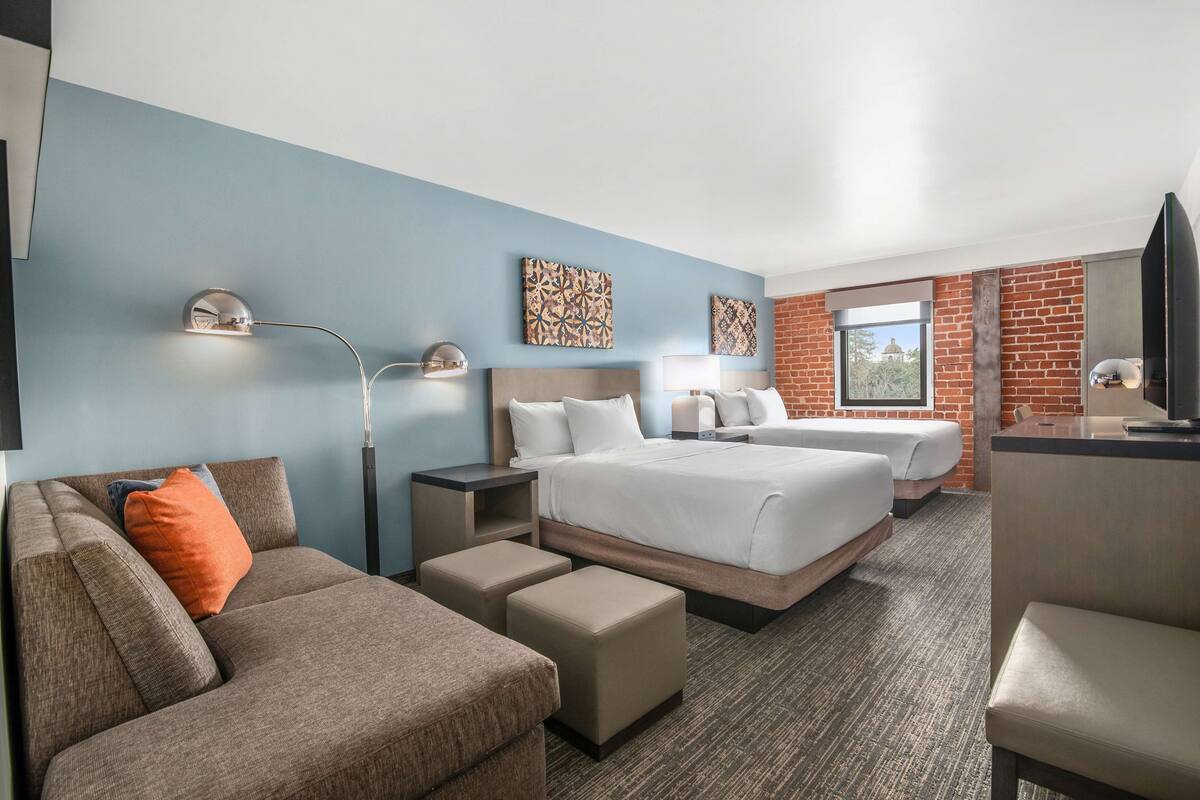 Een hotelkamer met een groot bed, twee nachtkastjes, een bureau, een stoel en een bank.