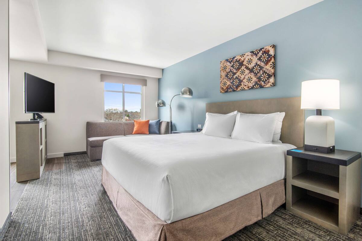 Een hotelkamer met een groot bed, een flatscreen televisie, een bureau en een raam.