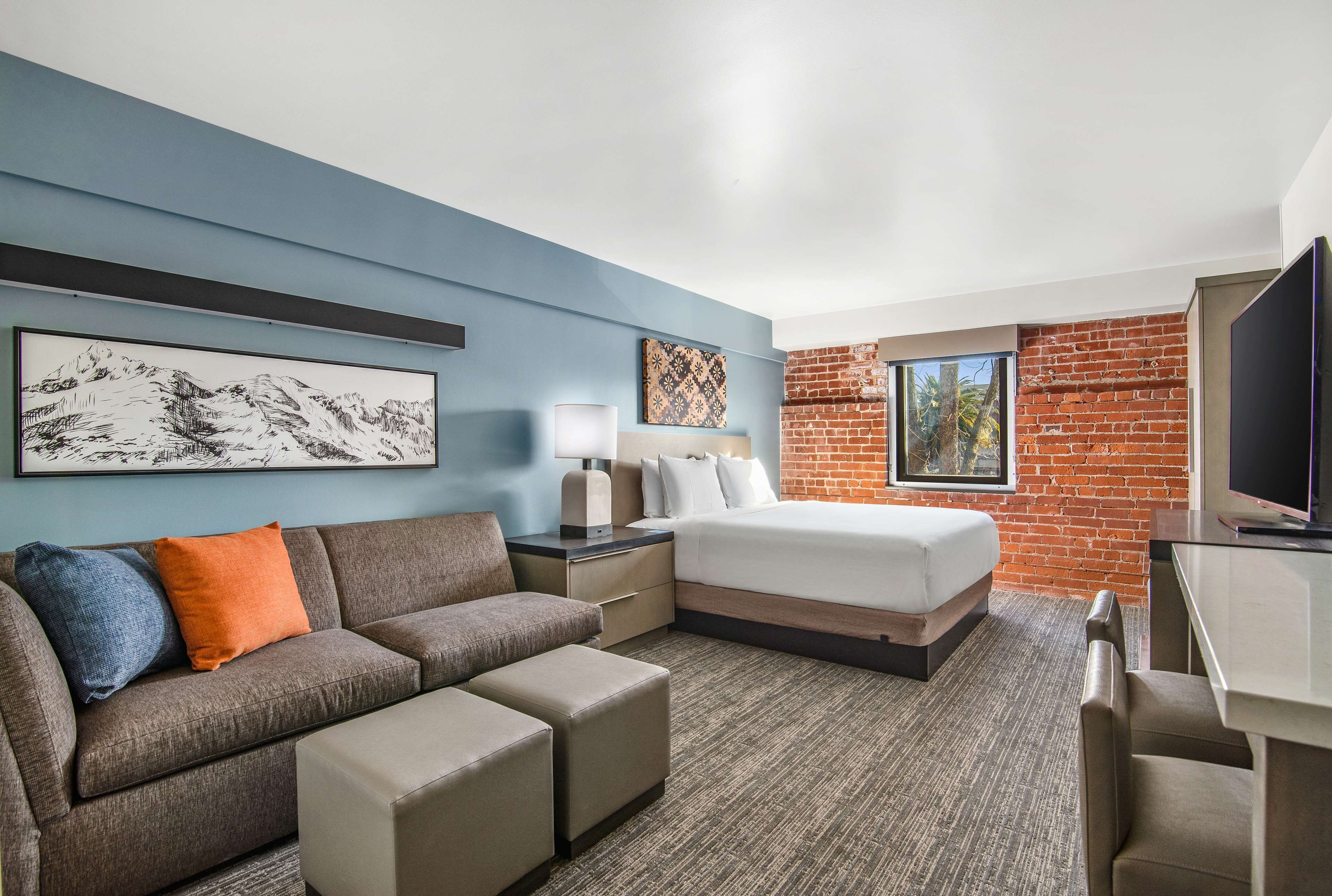 A hotel room with a bed, a sofa, a desk, and a TV.