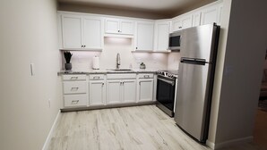 Una cocina moderna con armarios blancos, un refrigerador de acero inoxidable y un horno empotrado.